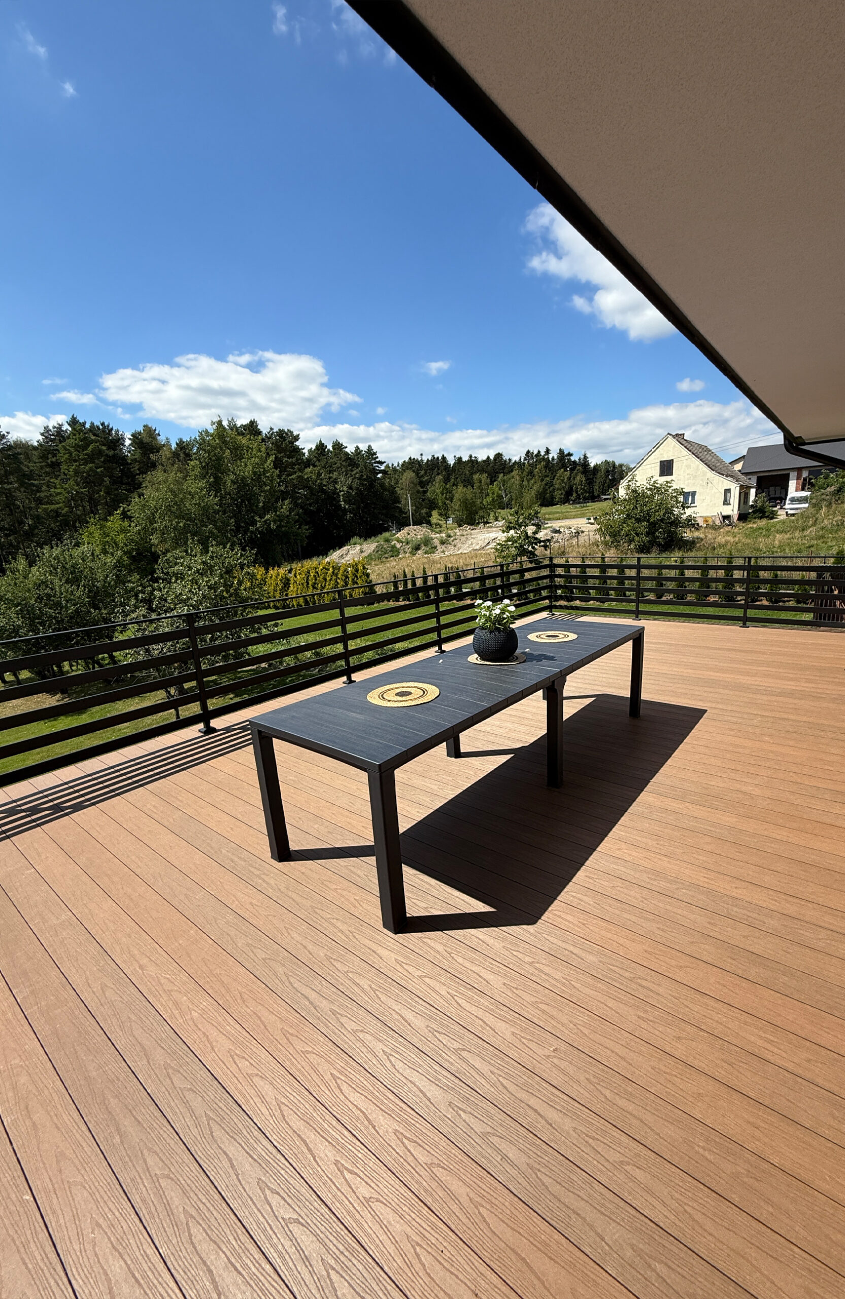 Low-maintenance composite decking creates a modern and functional outdoor living space, featuring a cozy seating area with a table, plant, and spectacular mountain views