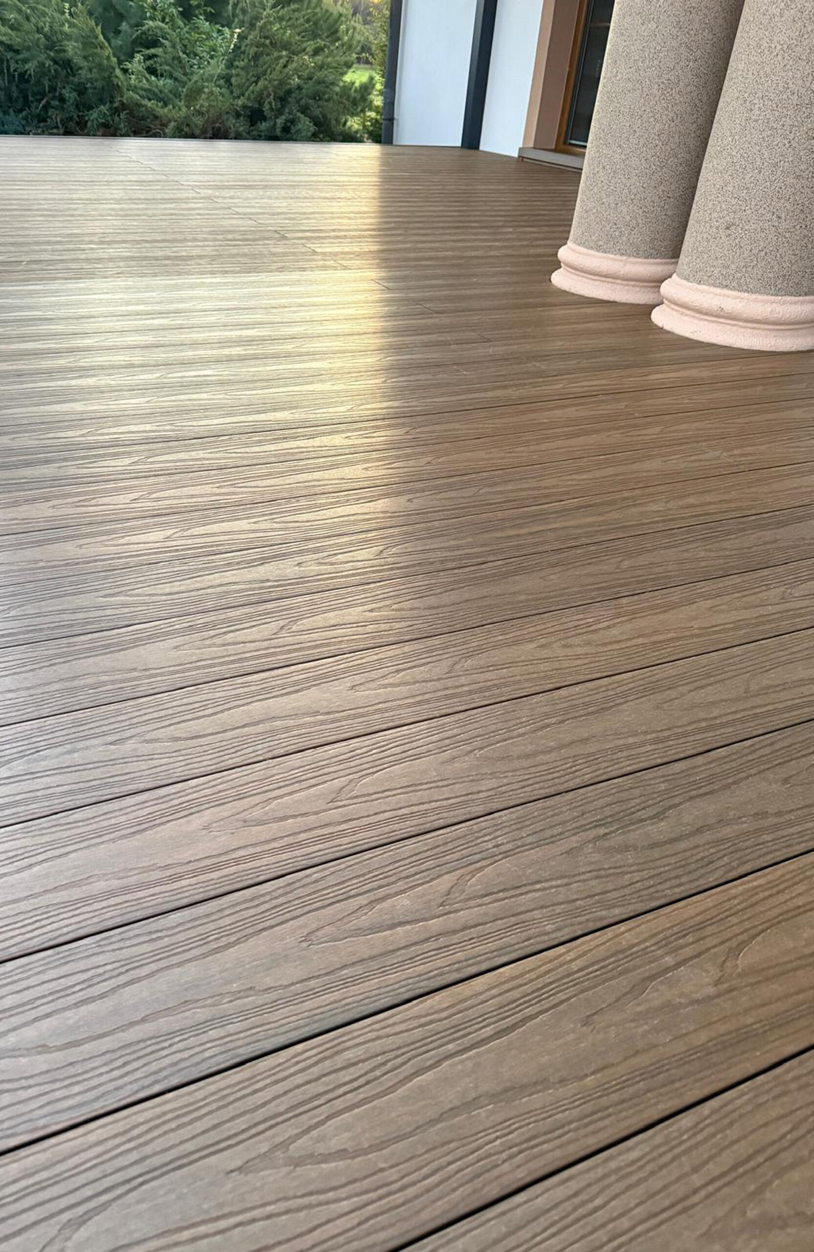 Durable and low-maintenance composite wood terrace decking installed on a home patio, featuring a realistic wood grain finish and a warm brown color