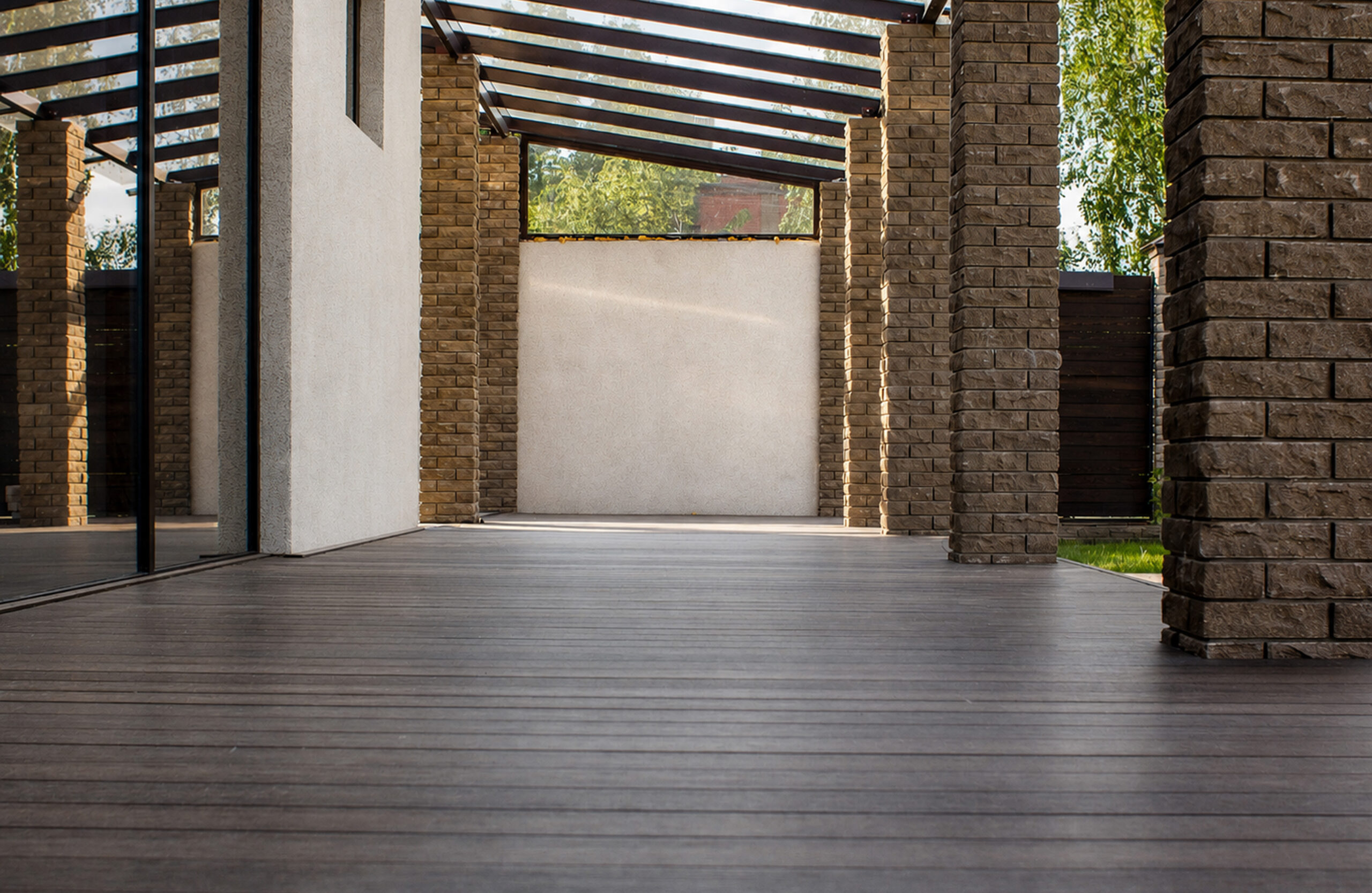 Covered terrace with walnut composite decking, brick columns and glass roof