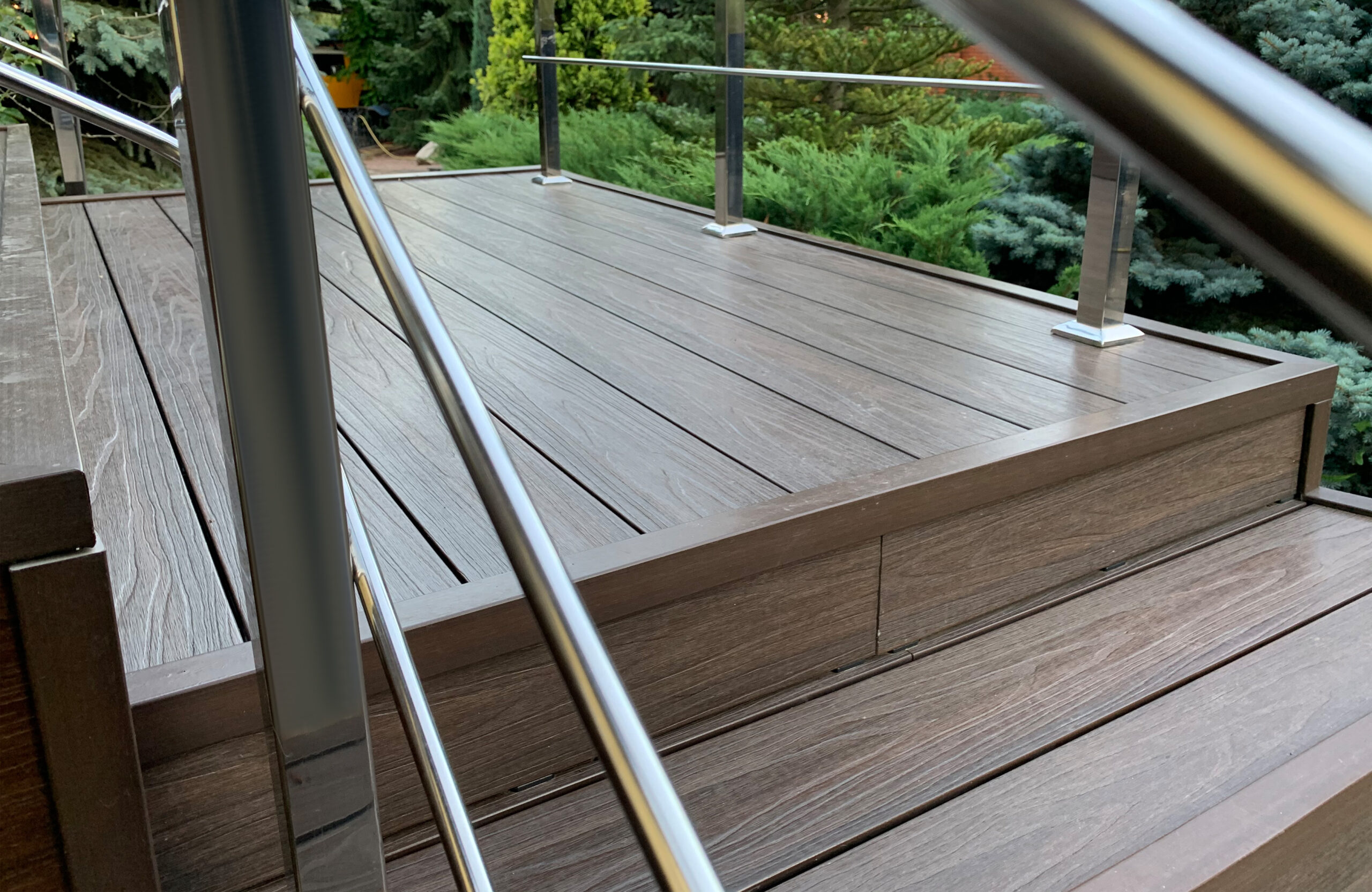 LEGRO walnut composite decking stairs with stainless steel railing in a landscaped garden