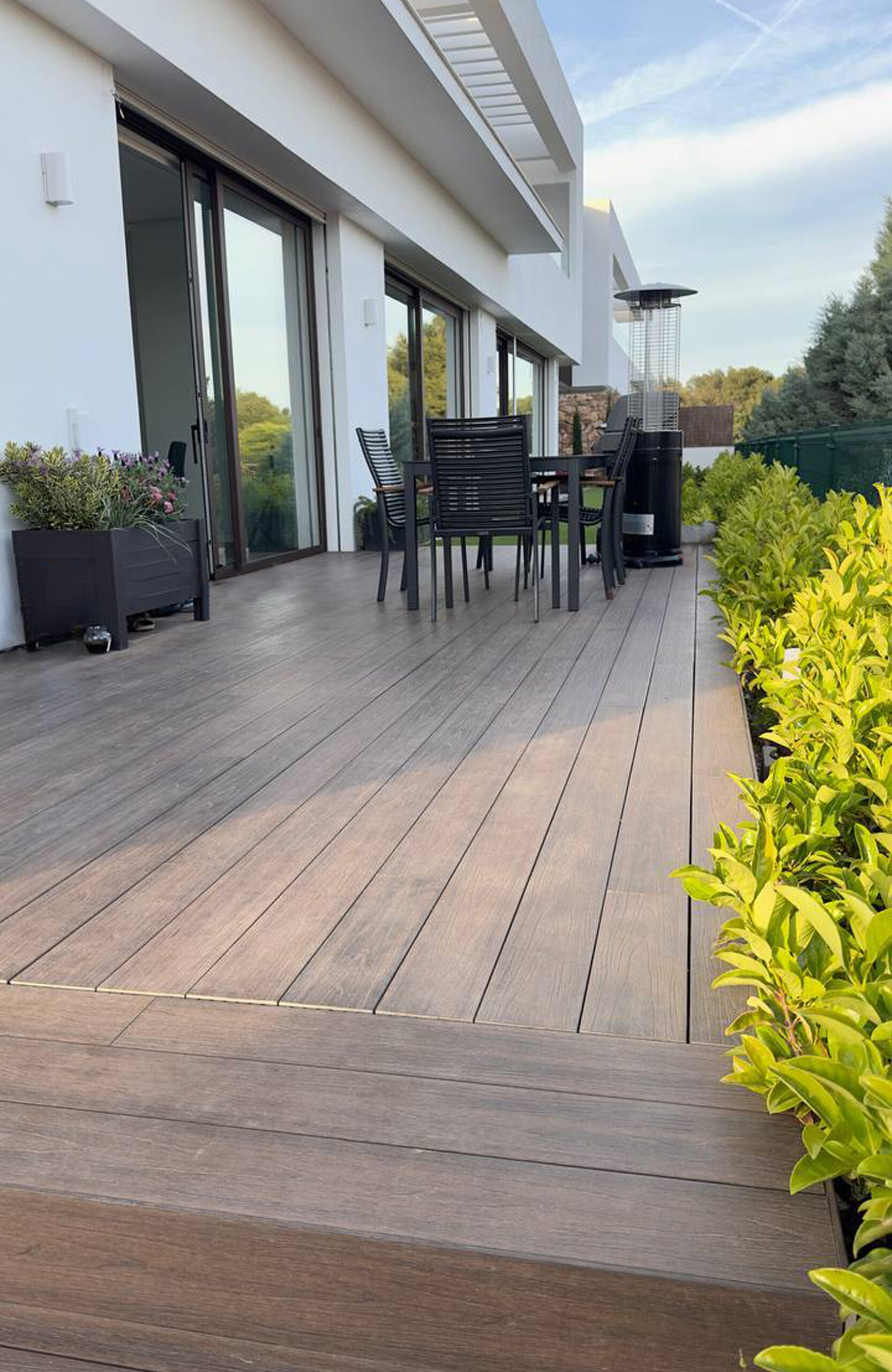 LEGRO walnut composite decking walkway along a modern house with garden plants