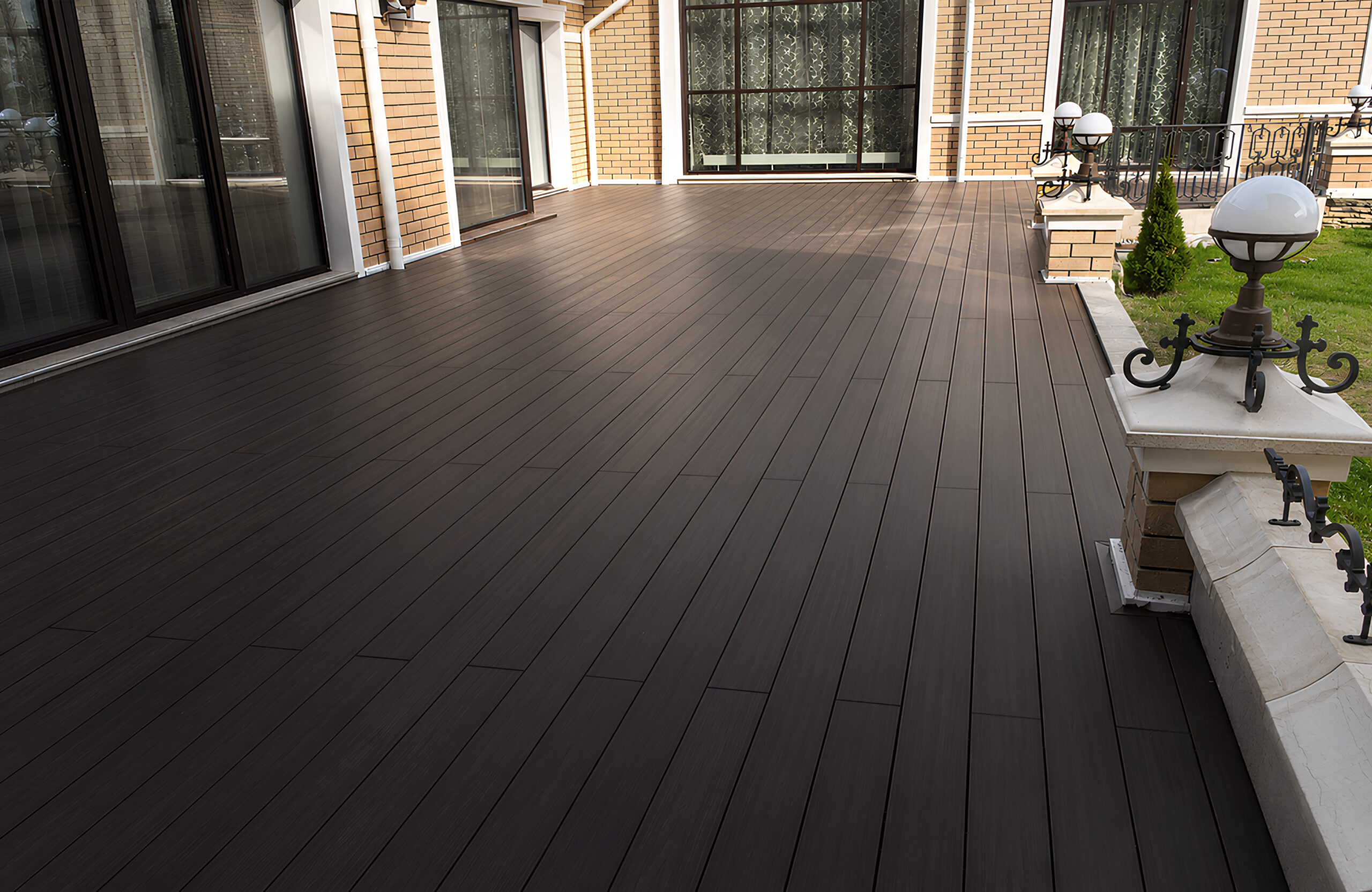 Spacious terrace with LEGRO walnut composite decking beside a brick house
