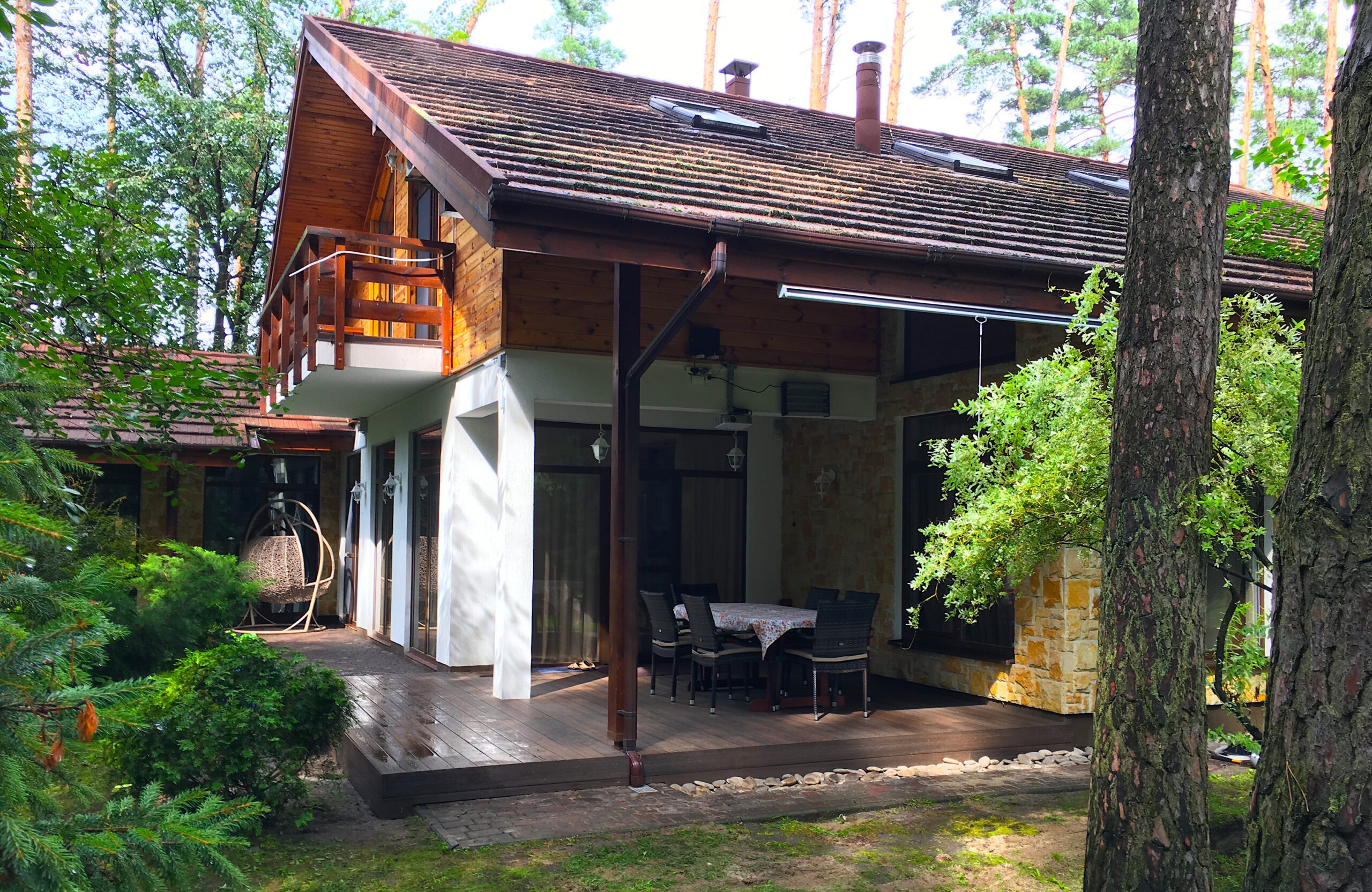 Covered terrace with LEGRO walnut composite decking surrounded by a pine forest