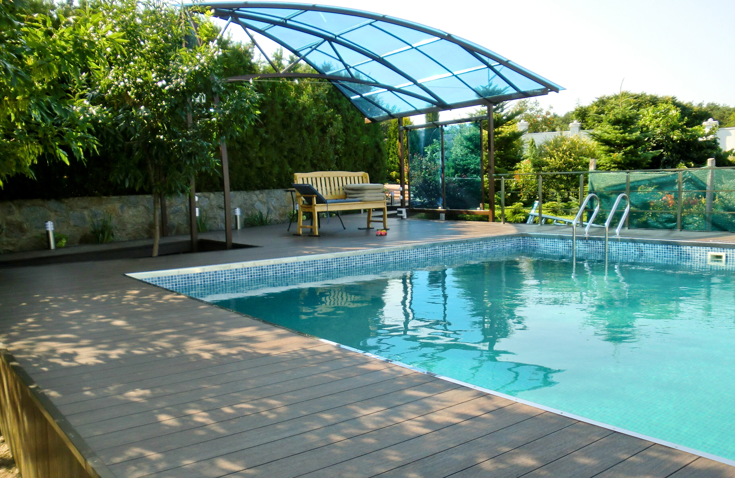 Swimming pool surrounded by LEGRO walnut composite decking with a covered seating area