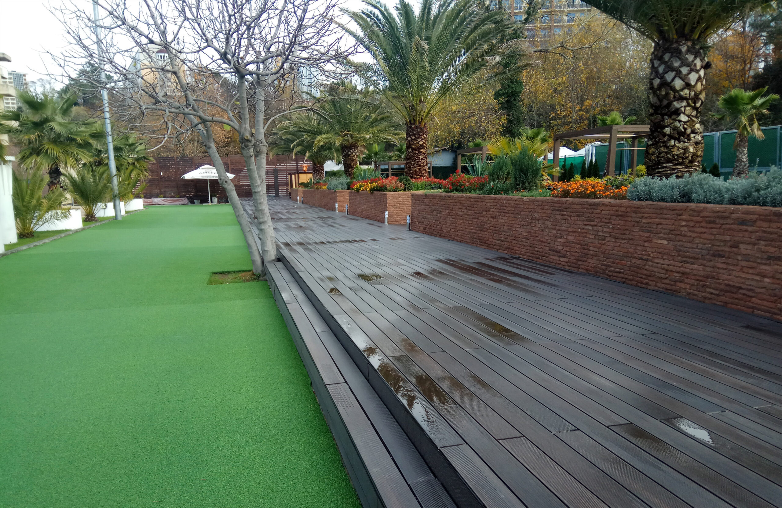 LEGRO walnut WPC decking with wide steps in a landscaped garden with palm trees