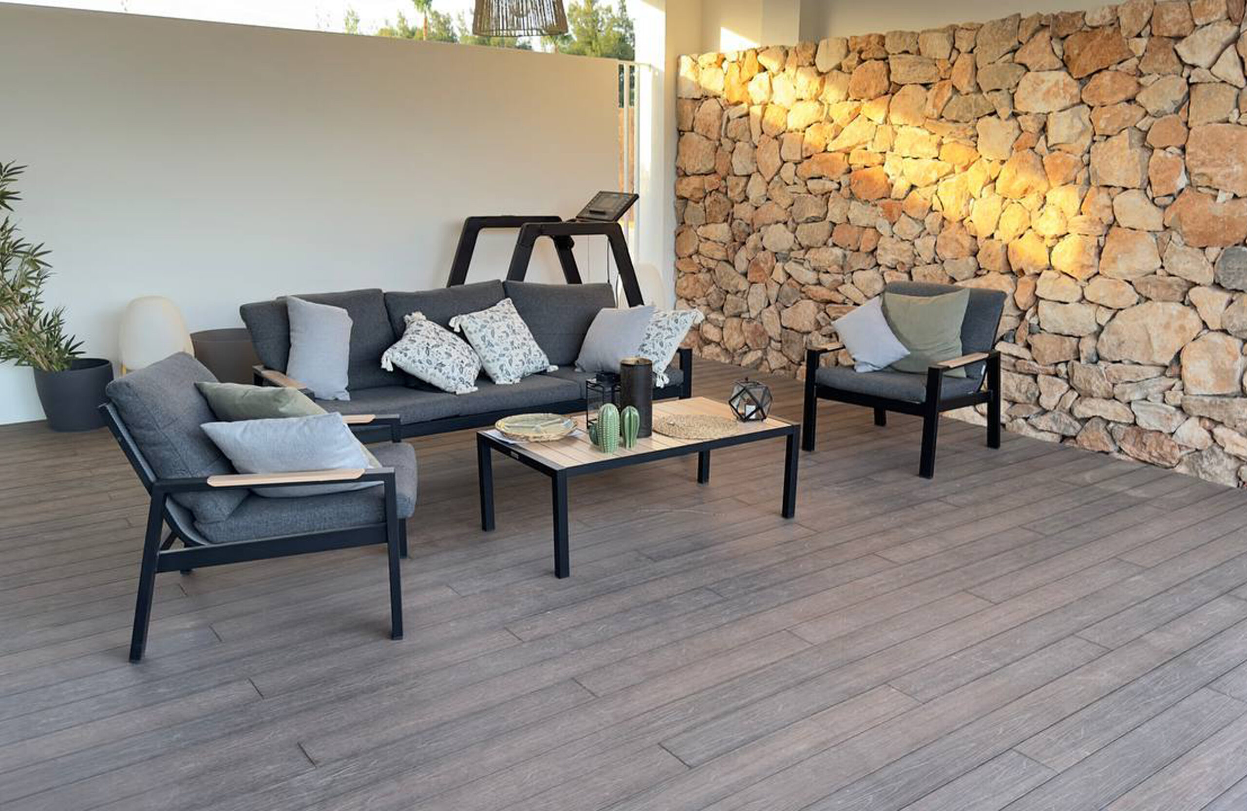 Covered outdoor lounge terrace with LEGRO walnut WPC decking and stone wall