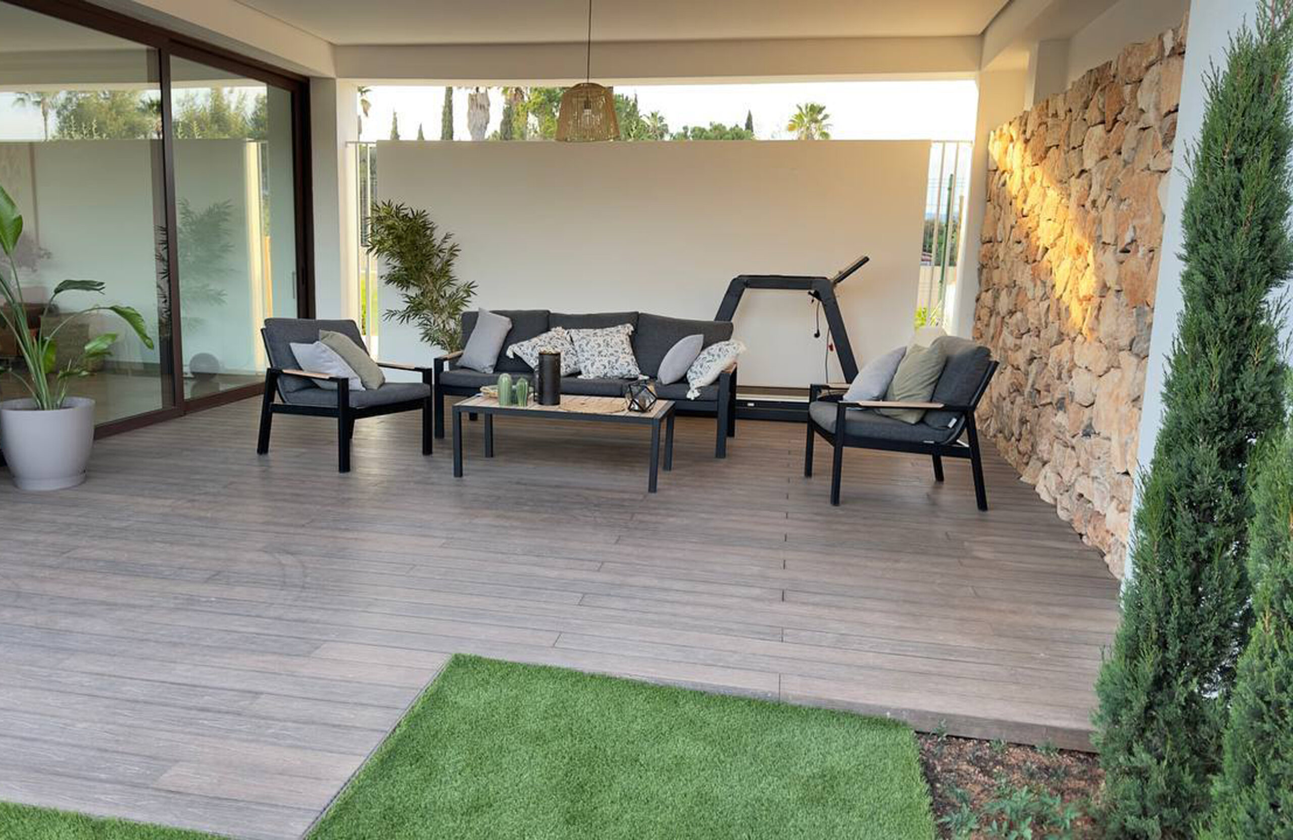 Covered outdoor lounge terrace with LEGRO walnut WPC decking and stone wall