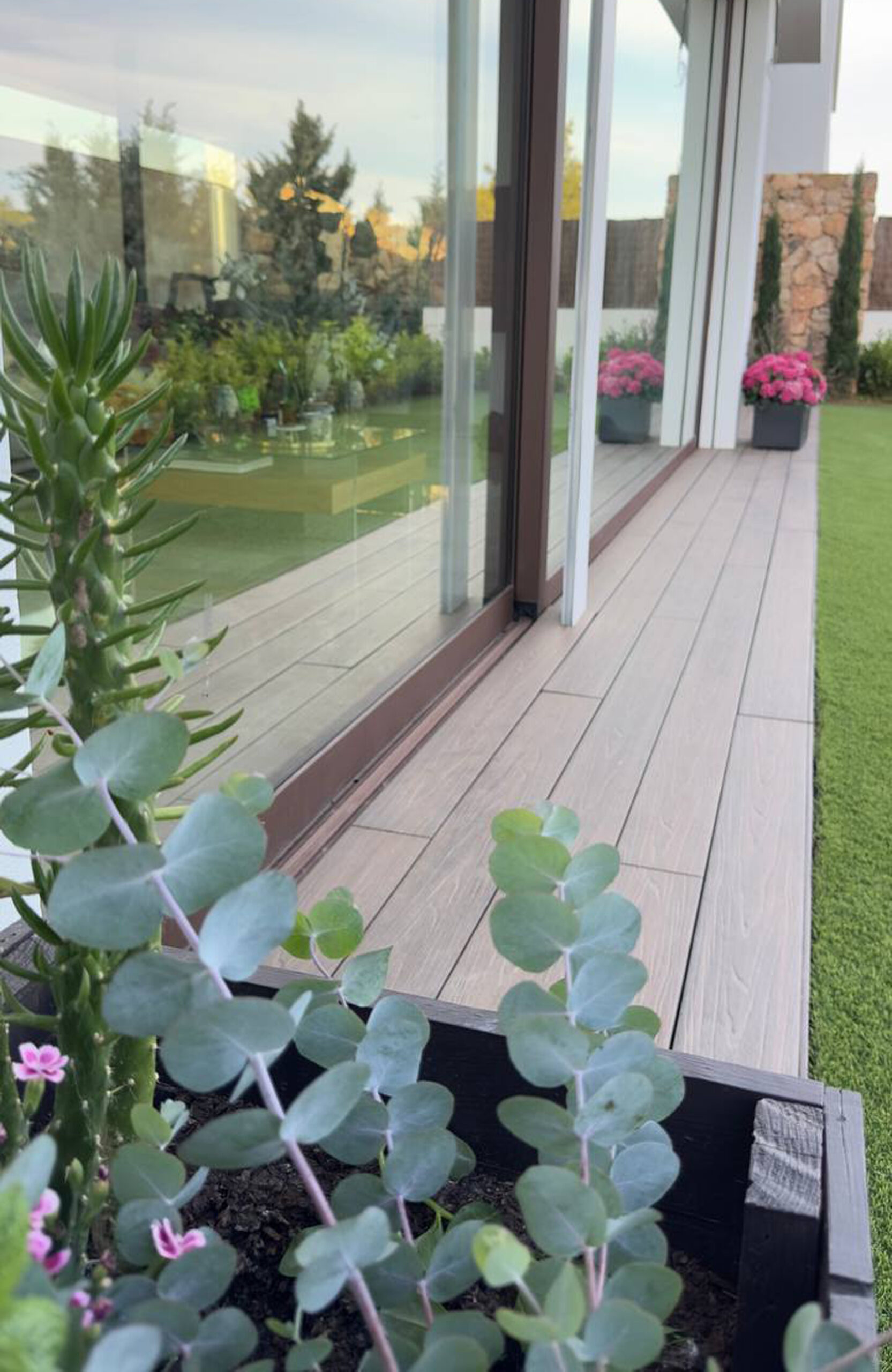 LEGRO walnut composite decking walkway along a modern house with garden plants