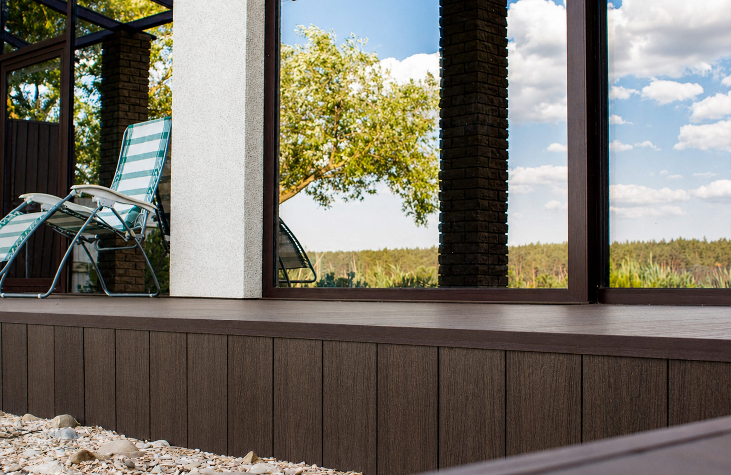 Close-up of walnut composite terrace decking and cladding beside large glass windows