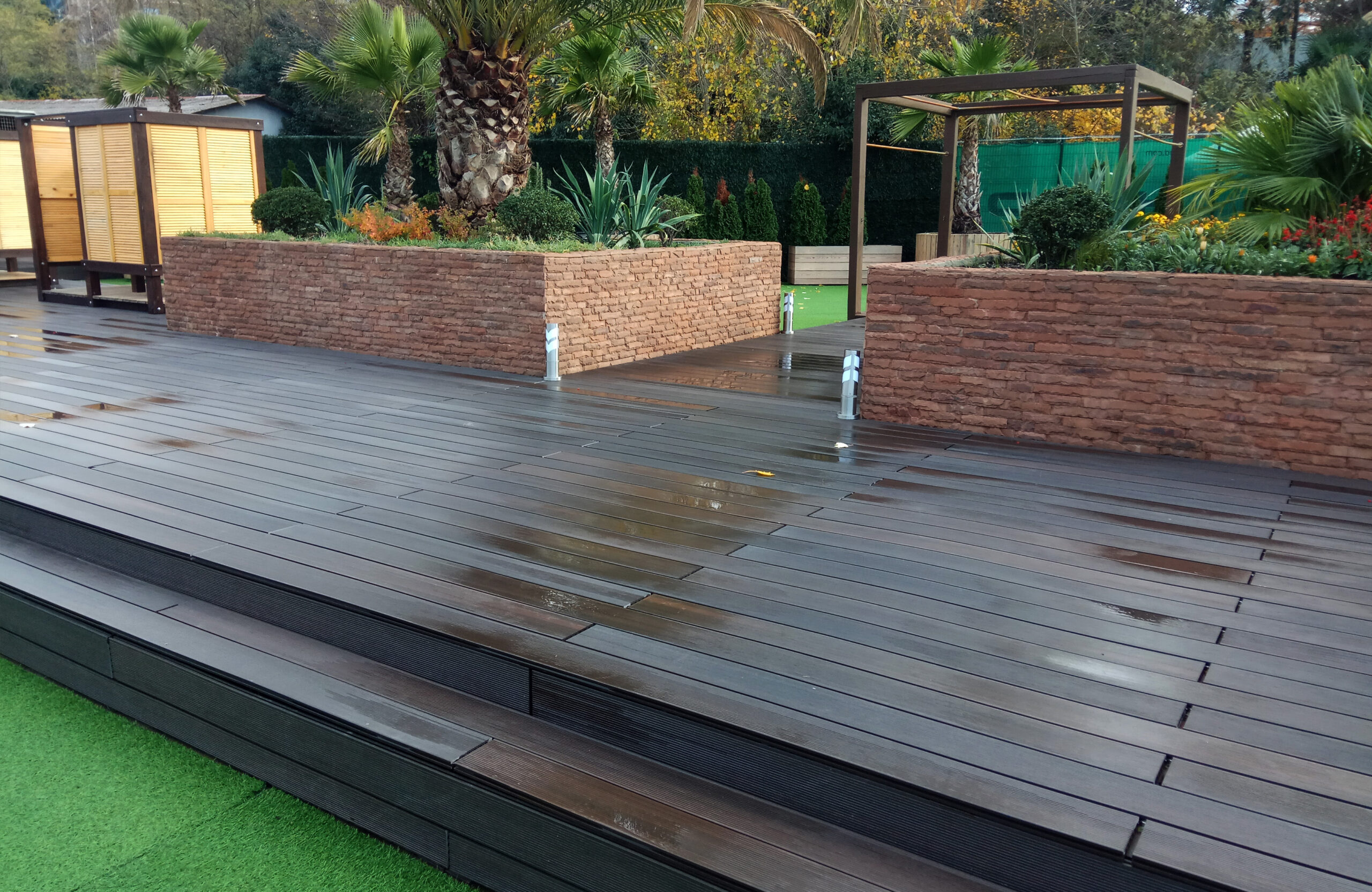 LEGRO walnut WPC decking with wide steps in a landscaped garden with palm trees