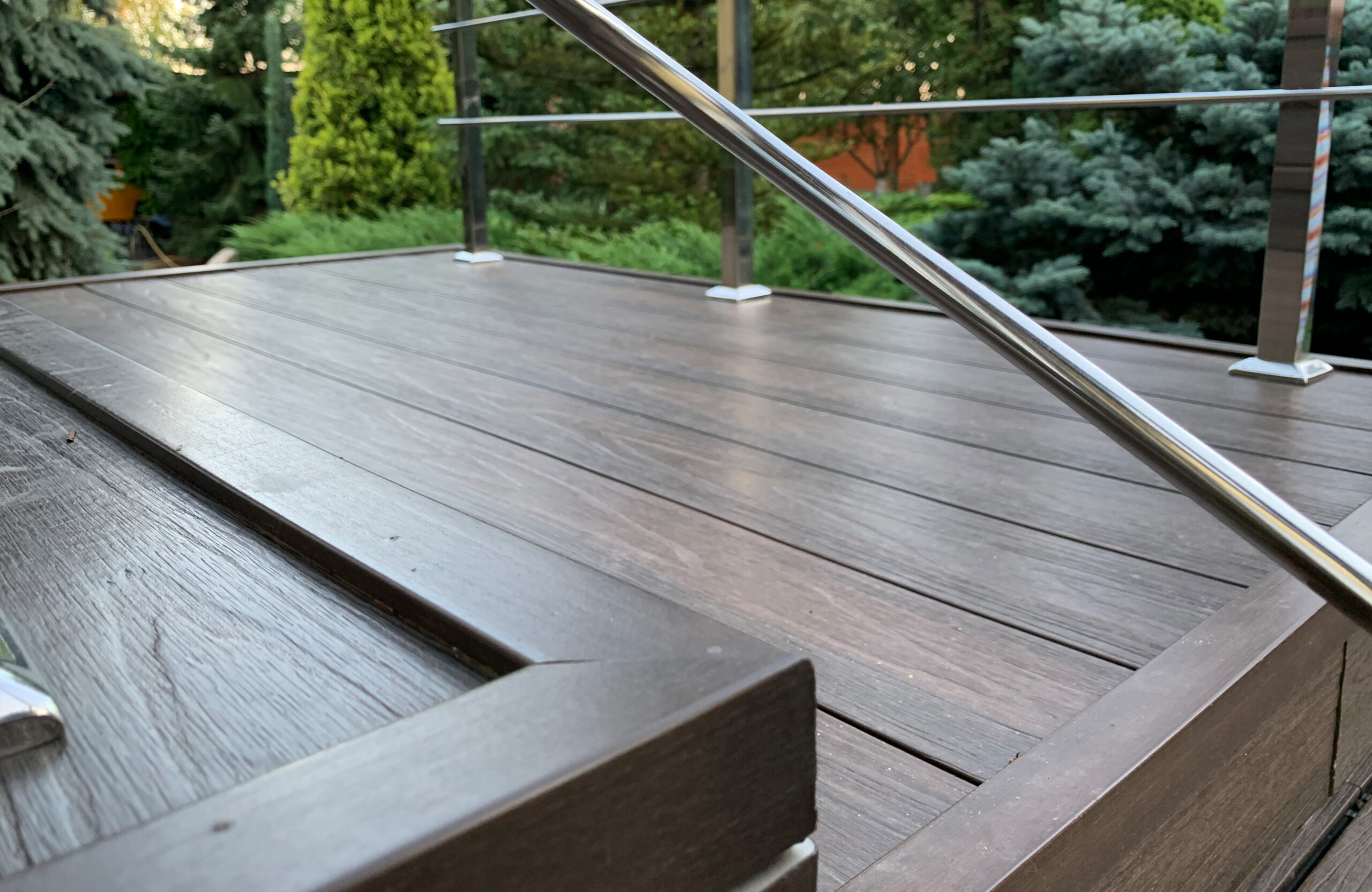 Close-up of LEGRO walnut composite decking stairs with modern stainless steel railing