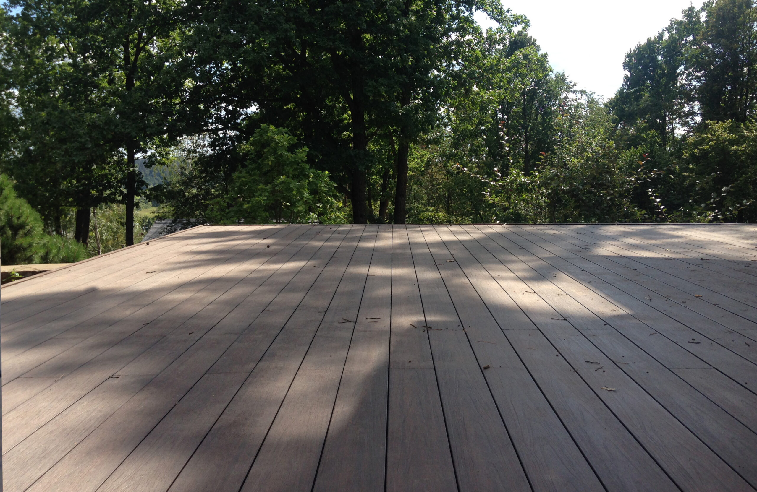 Large outdoor terrace with LEGRO walnut composite decking in a wooded setting