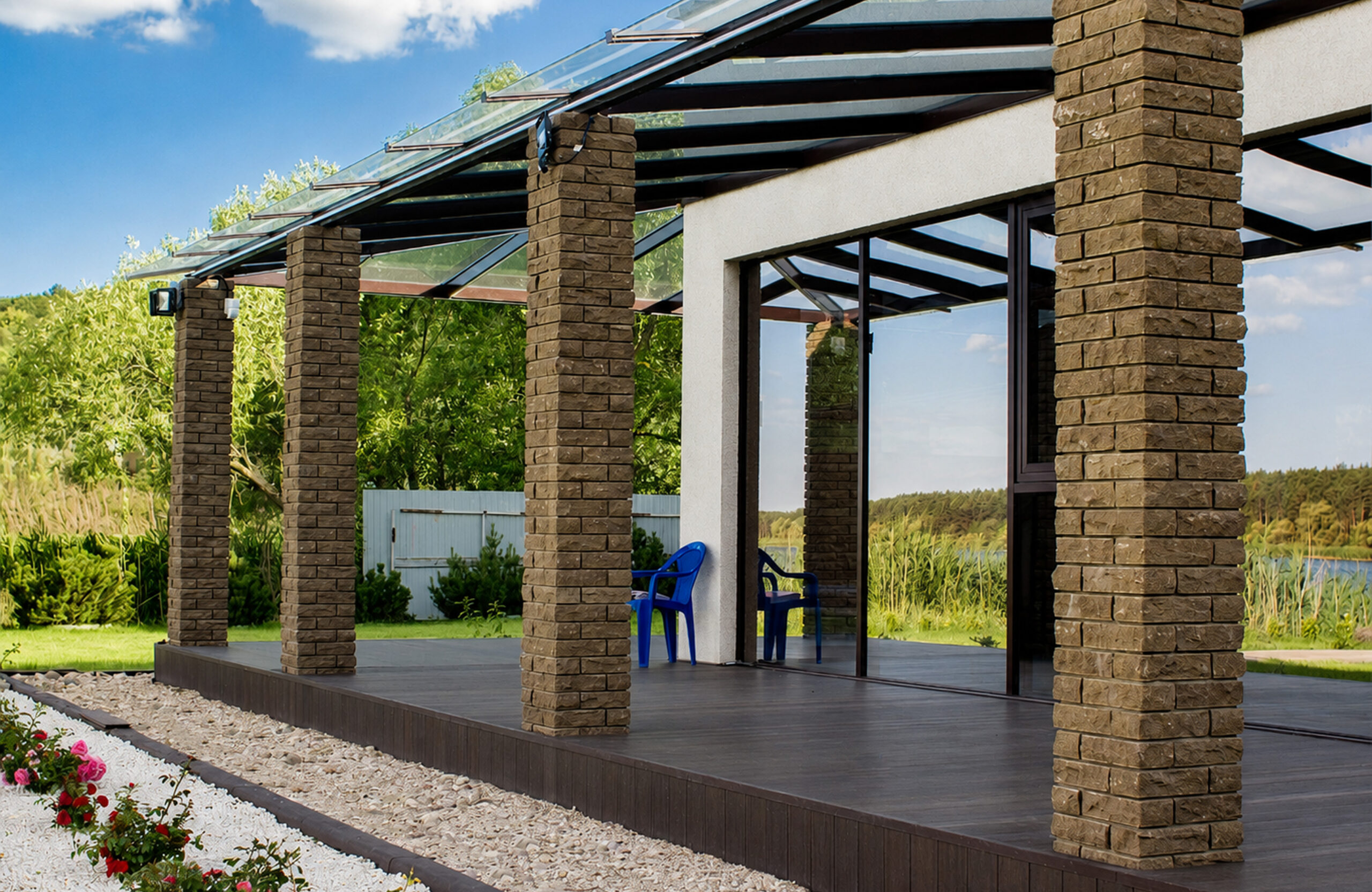 Modern covered terrace with dark composite decking, brick pillars and glass canopy