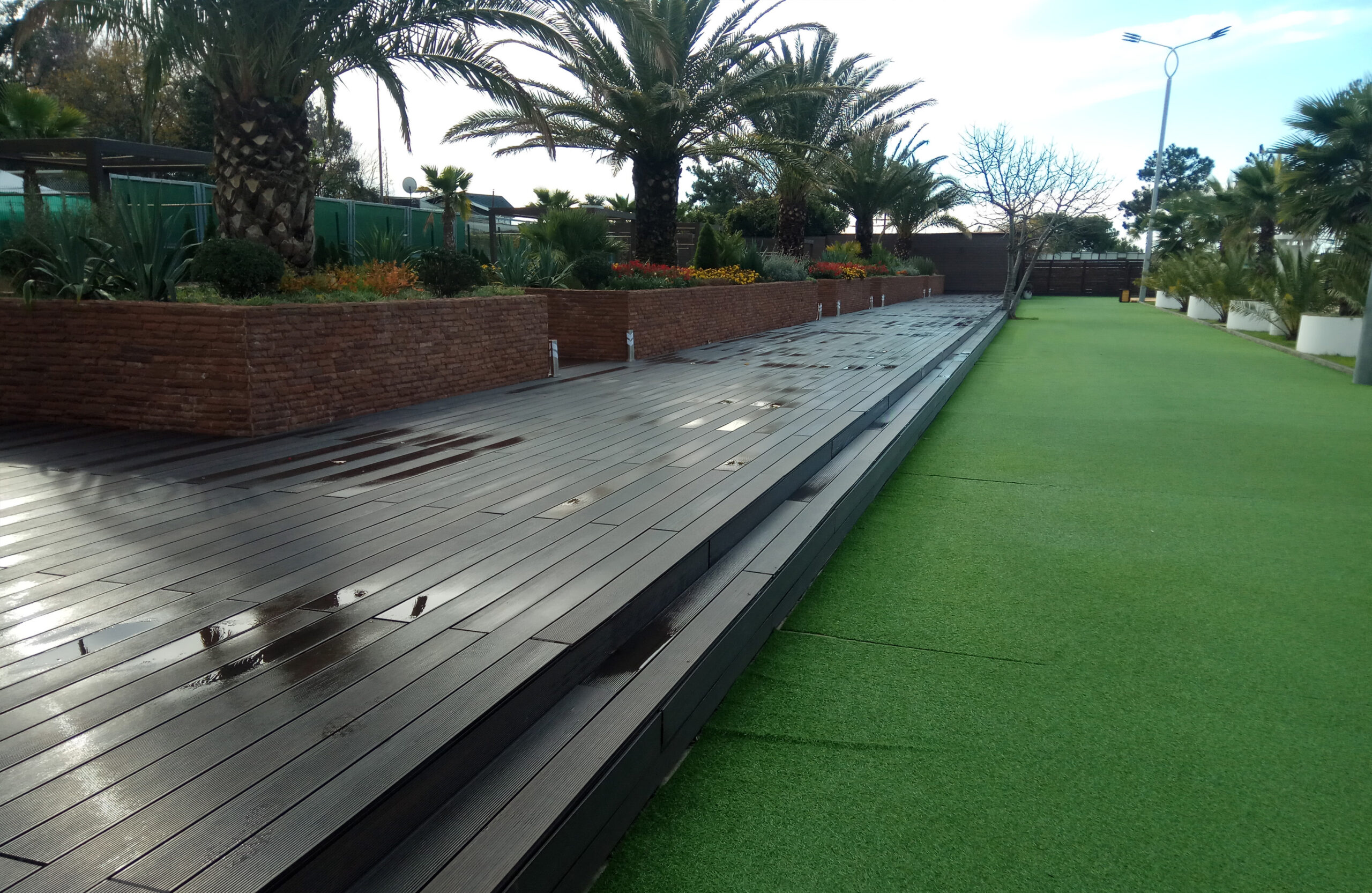 LEGRO walnut WPC decking with wide steps in a landscaped garden with palm trees