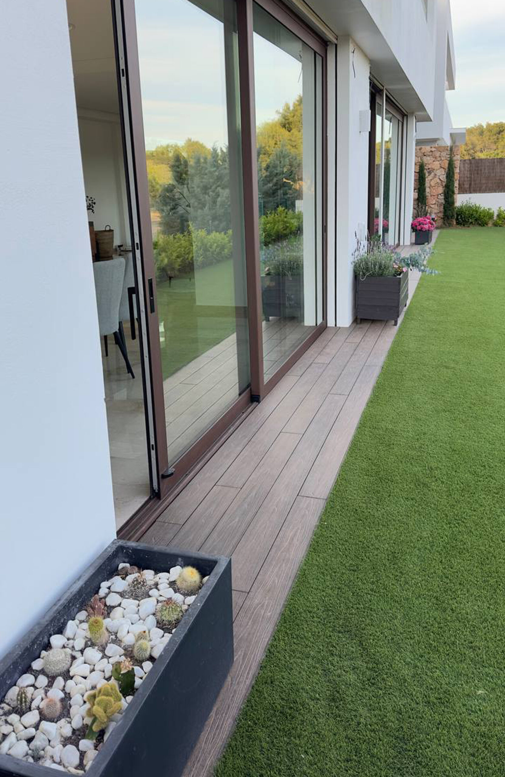 LEGRO walnut composite decking walkway along a modern house with garden plants