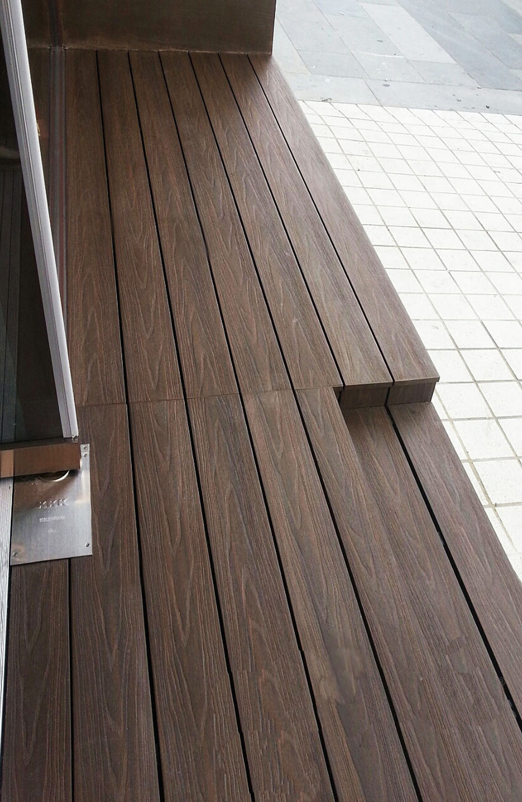 A detailed, close-up photograph of durable walnut-colored wood-plastic composite decking planks installed on an outdoor patio floor