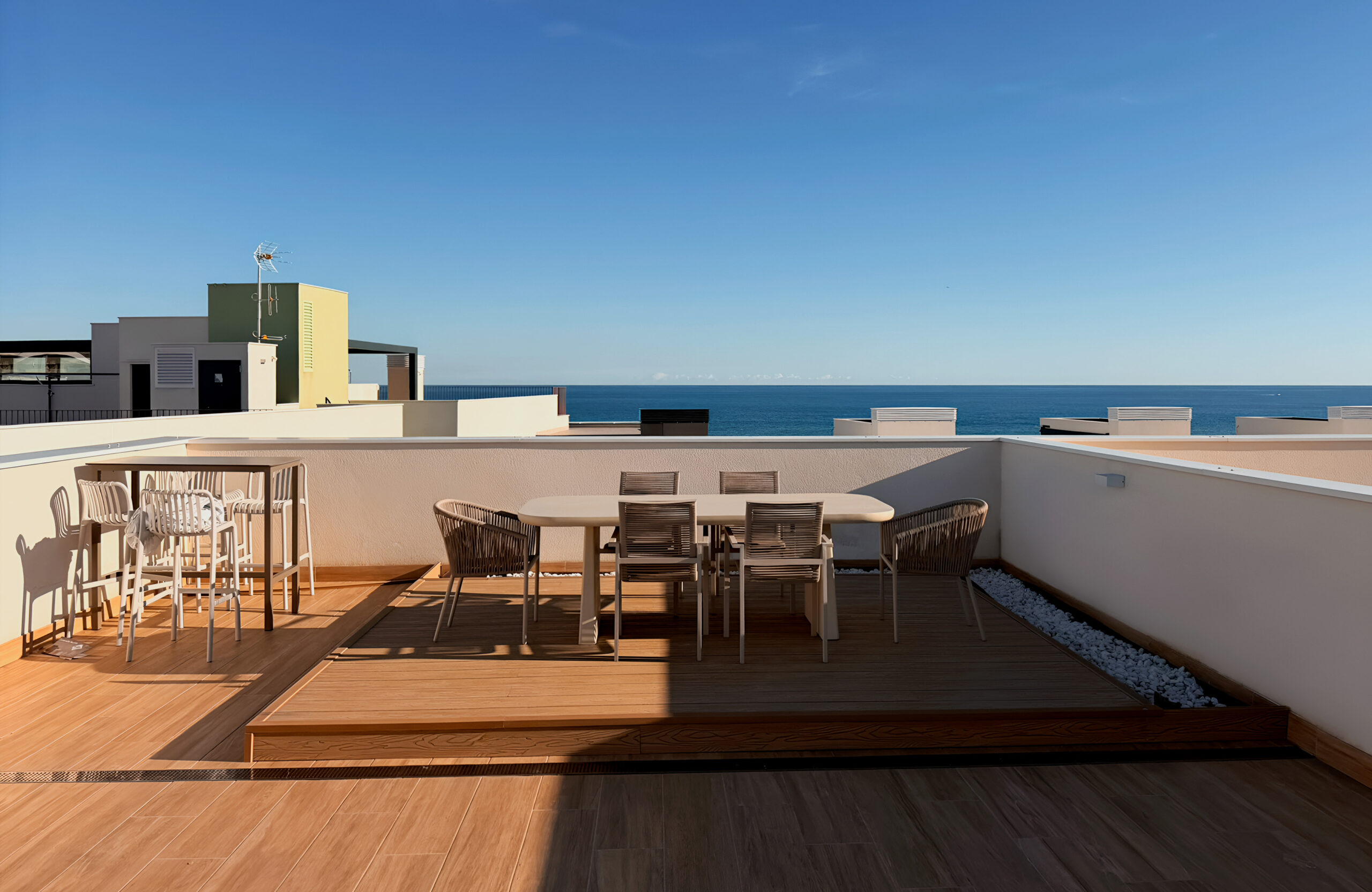 Bruggan Elegant Copper Natural decking creates a raised rooftop dining area overlooking the sea