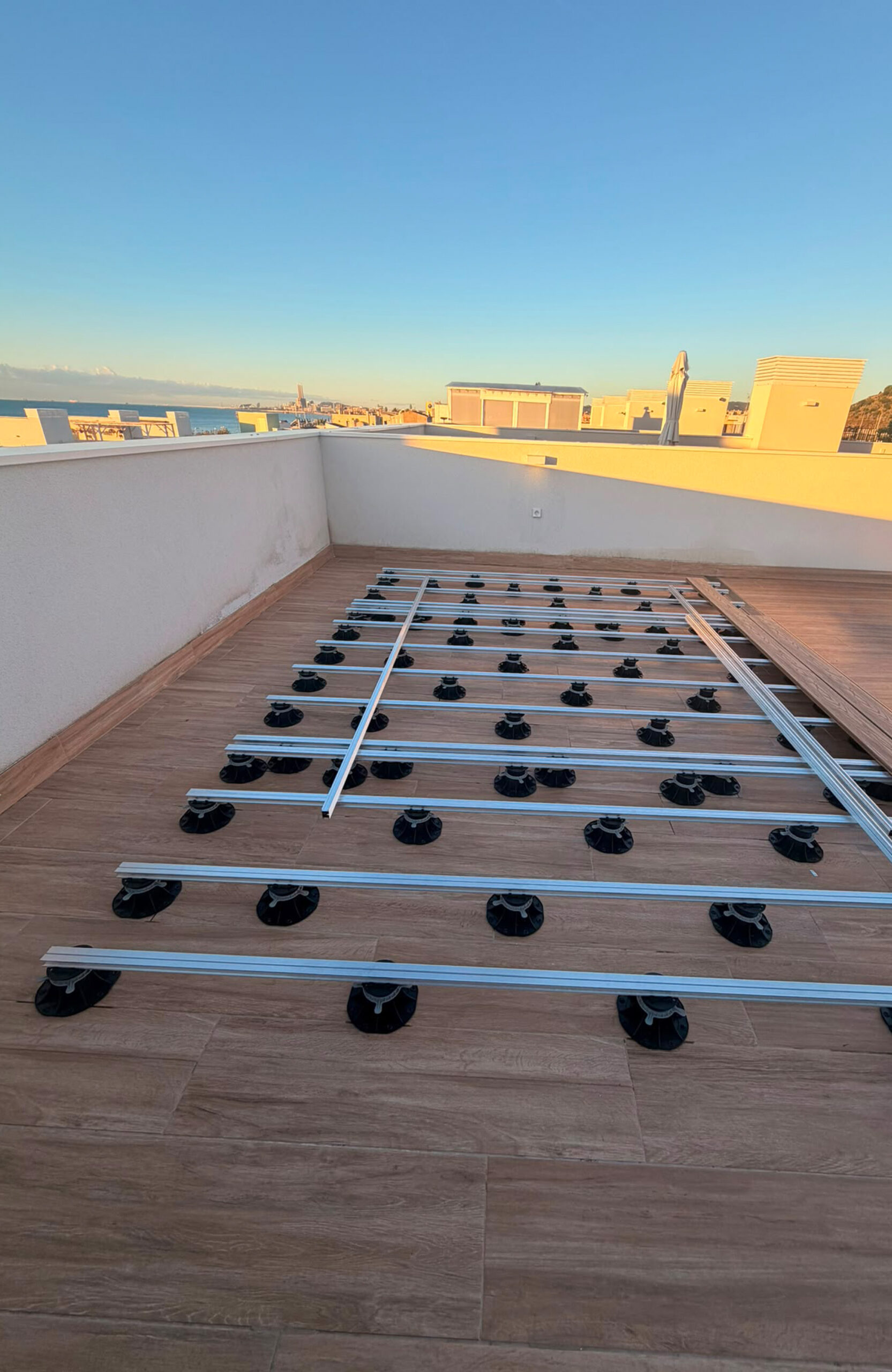Aluminum joists rest on adjustable pedestal supports, forming a substructure for rooftop decking