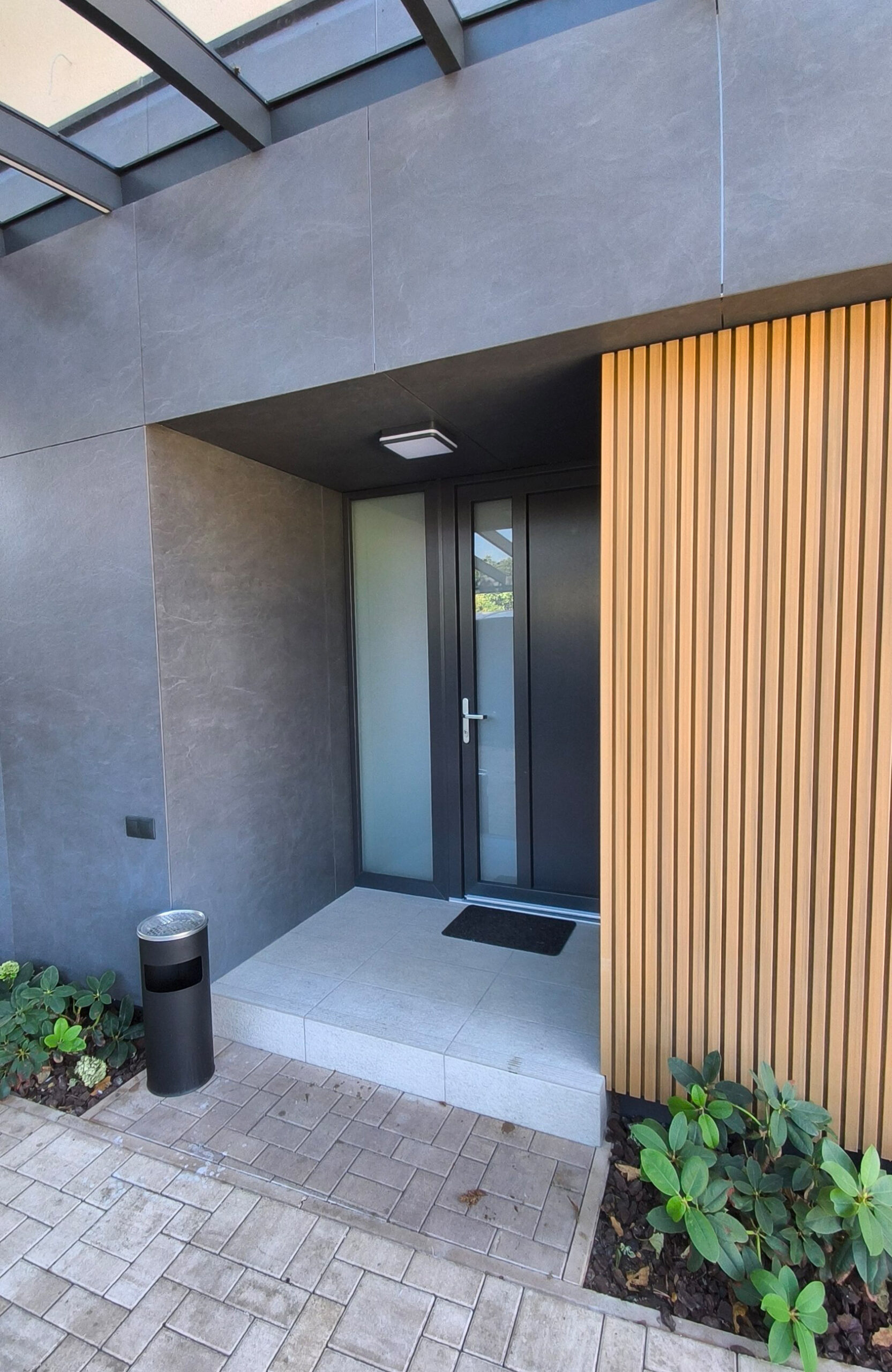 Modern house entrance with LEGRO FS15 Maple vertical facade boards and dark exterior finishes