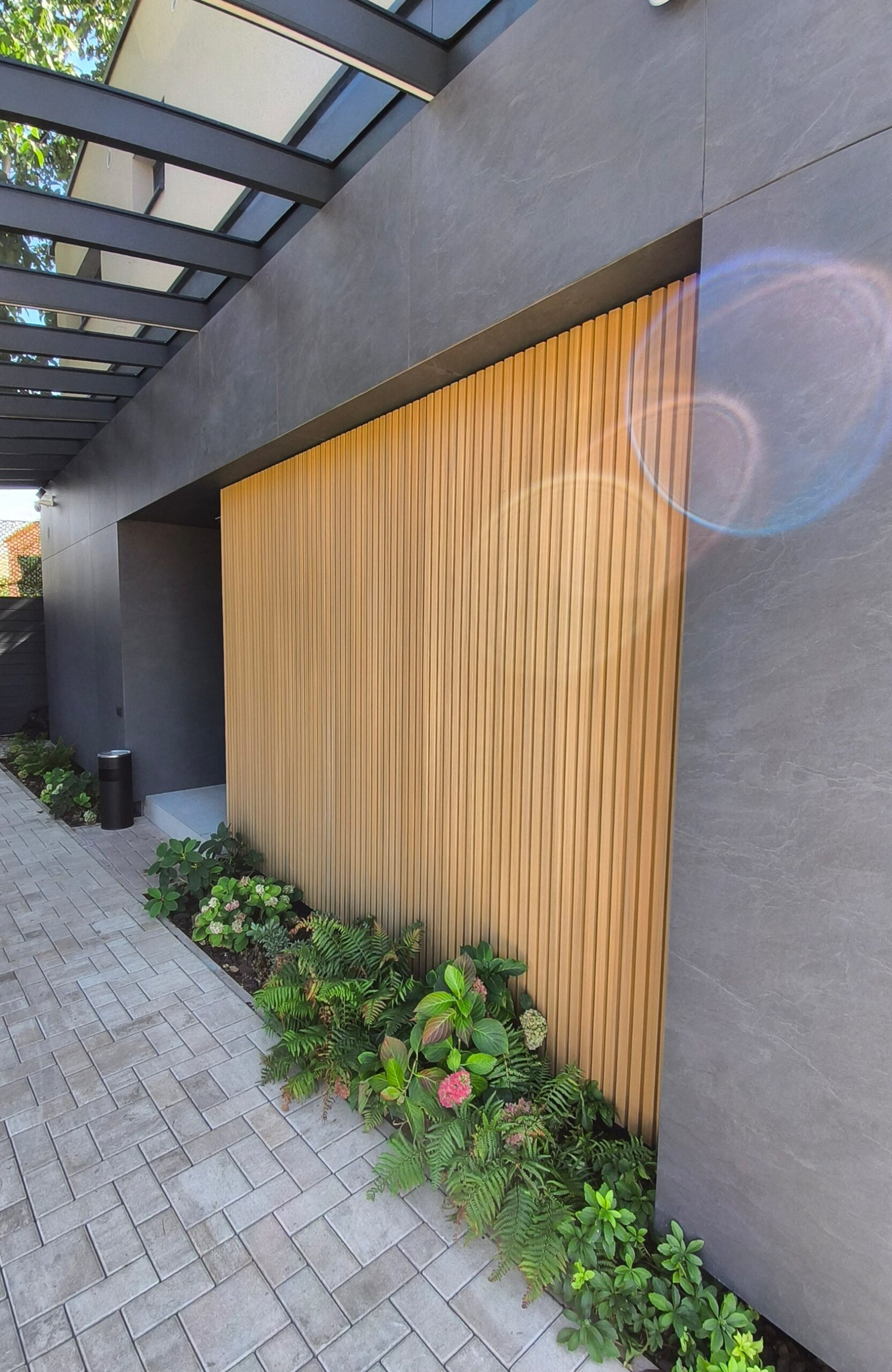 Modern house entrance with vertical LEGRO FS15 Maple WPC facade cladding and dark grey exterior panels