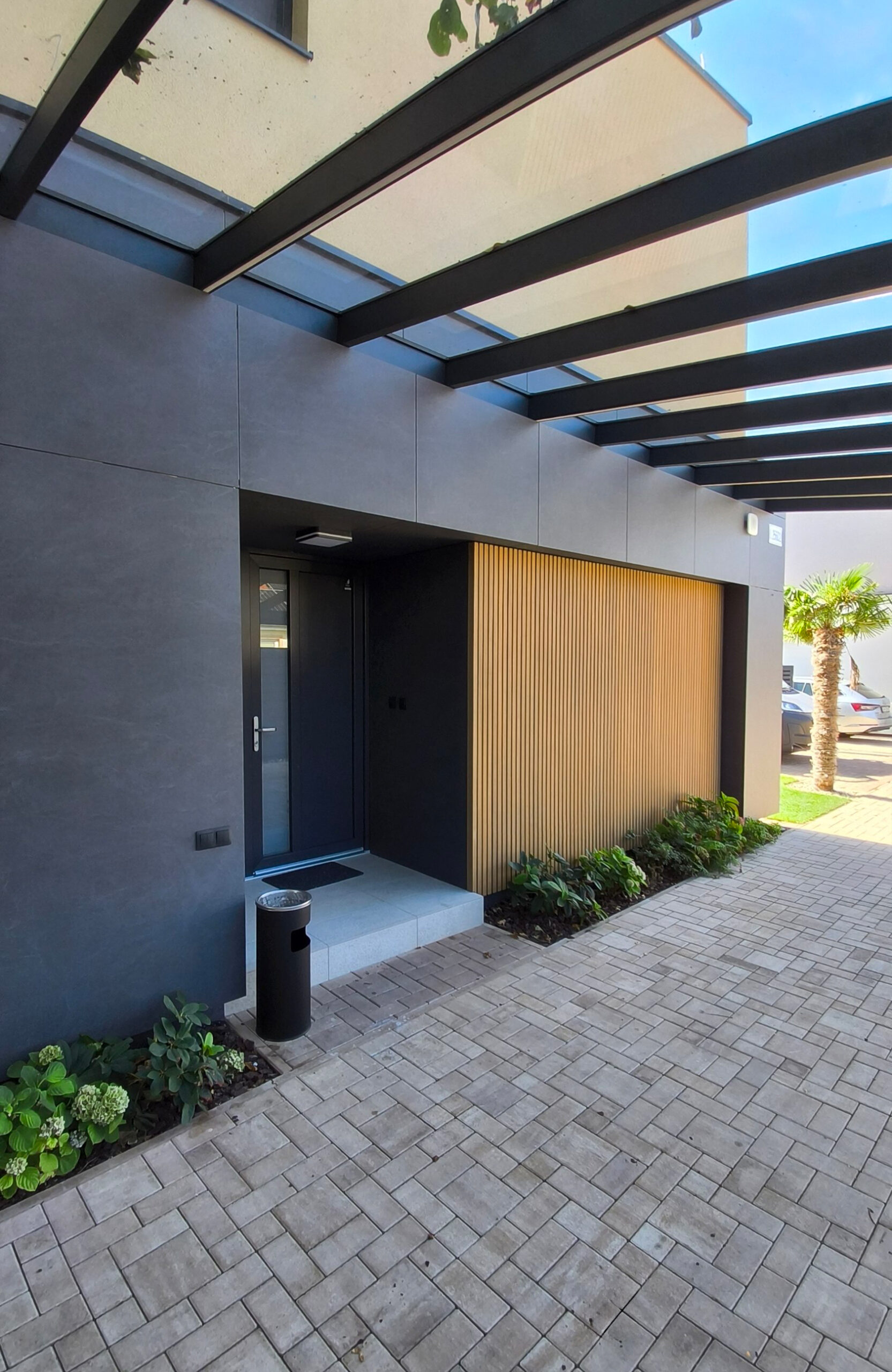Contemporary home exterior with LEGRO FS15 Maple facade cladding and glass entrance canopy