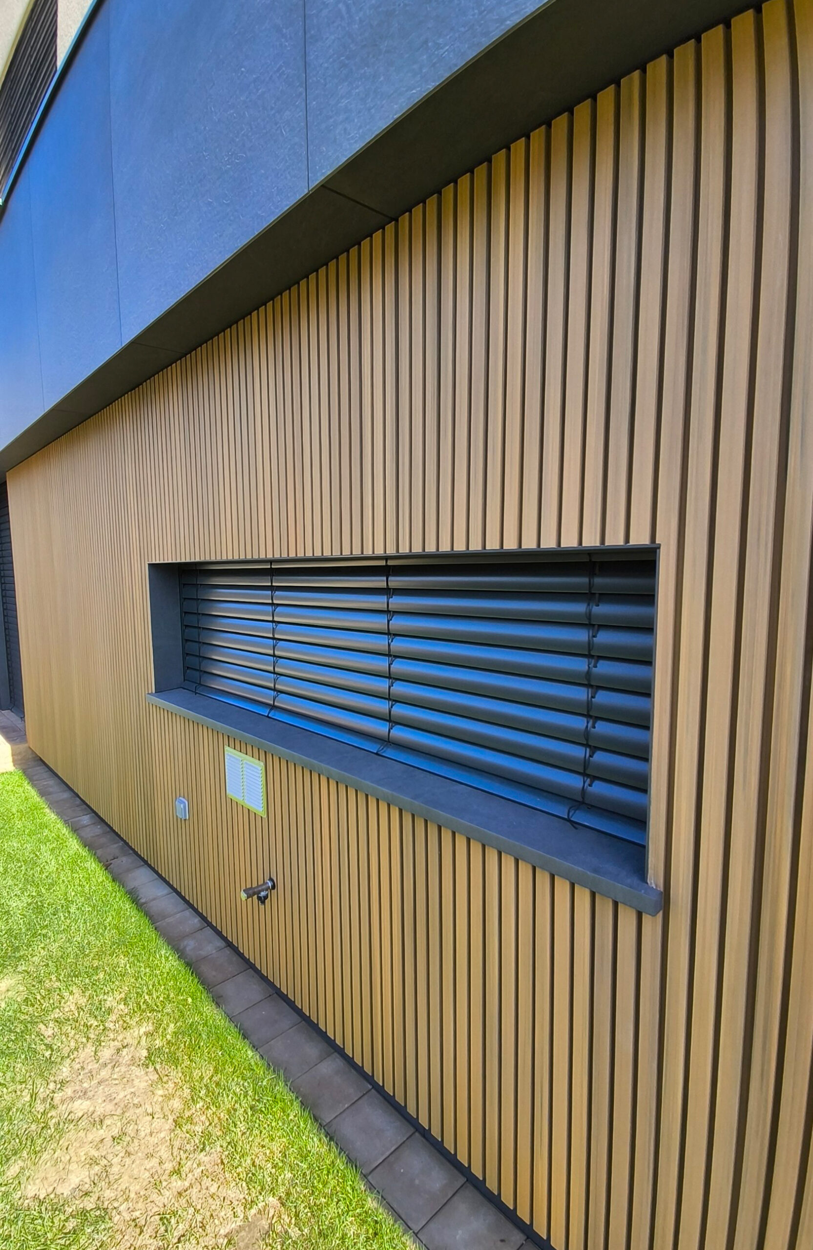 Close-up of LEGRO FS15 Maple vertical WPC facade cladding around a window in Bratislava, Slovakia